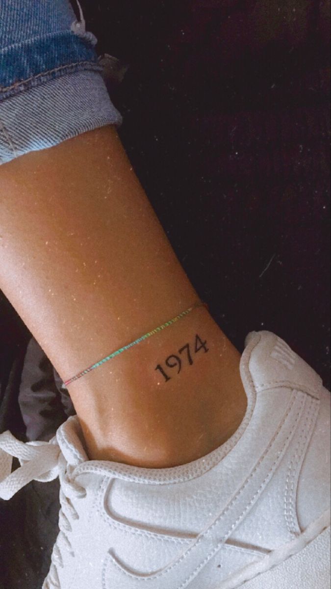 a woman's foot with a small tattoo on her left ankle and the word 477 written in black ink