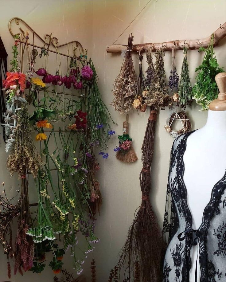 an assortment of dried flowers and plants hanging on a wall next to a mannequin