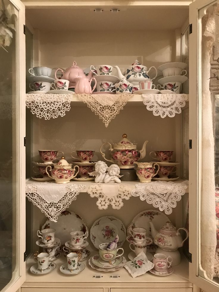 an old china cabinet filled with tea cups and saucers