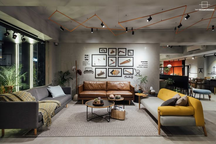 a living room filled with lots of furniture next to a large glass wall covered in pictures