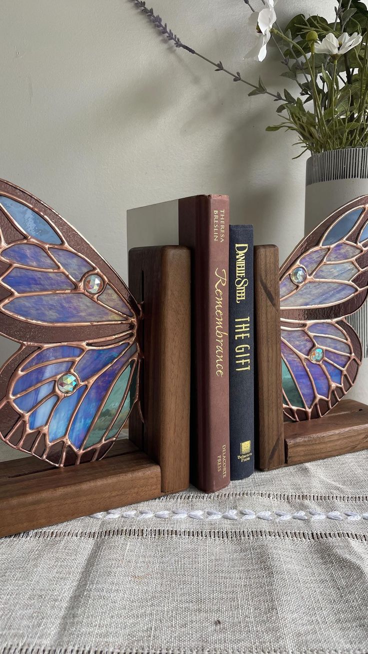 two butterfly bookends sitting on top of a table next to a vase with flowers