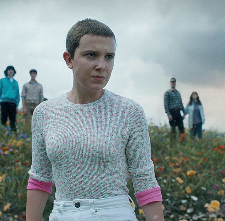 a woman standing in front of a group of people on top of a grass covered field