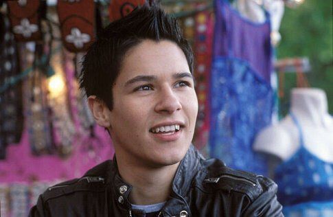 a young man in a leather jacket smiles at the camera