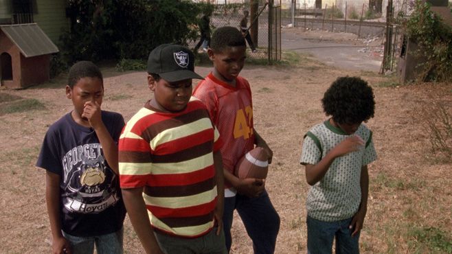 four young boys are standing outside in the grass