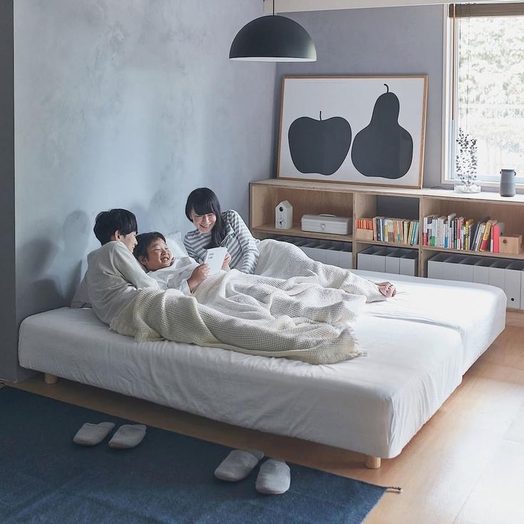 three people laying on a bed in a room