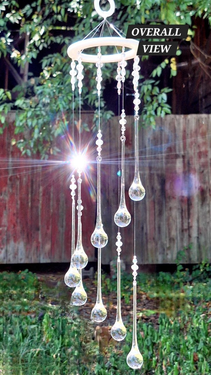 a wind chime hanging from a tree in front of a fence with the words overall view on it