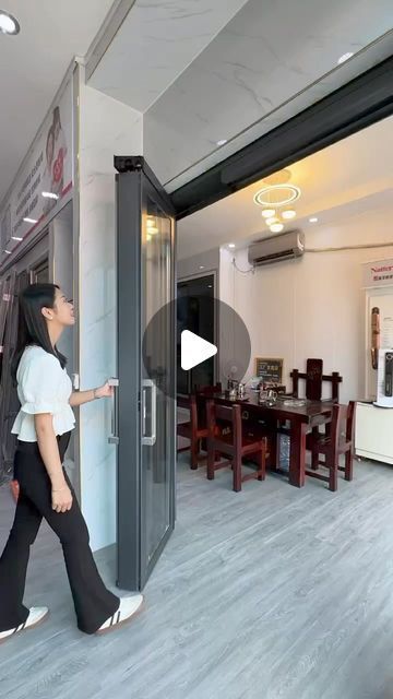 a woman is walking through an open door in the middle of a room with tables and chairs