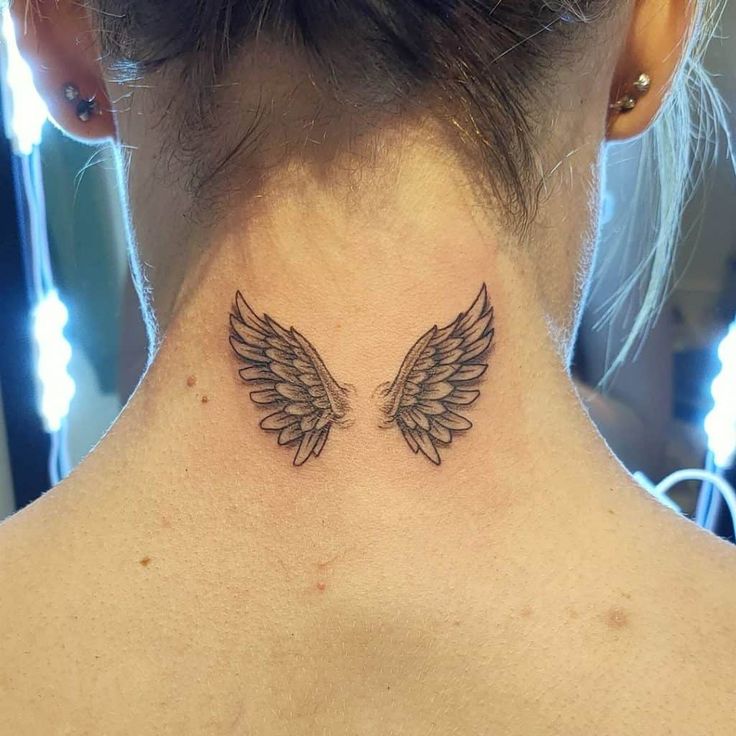 the back of a woman's neck with two angel wings on her left side