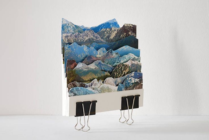 there are two hooks on the wall with mountains painted on them and one is hanging from it's side