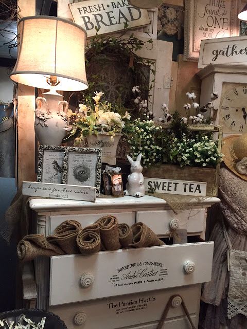 an old fashioned dresser with flowers and other items on it in a store window display