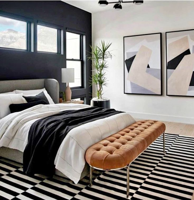 a bedroom with black and white decor and artwork on the wall, along with a bench