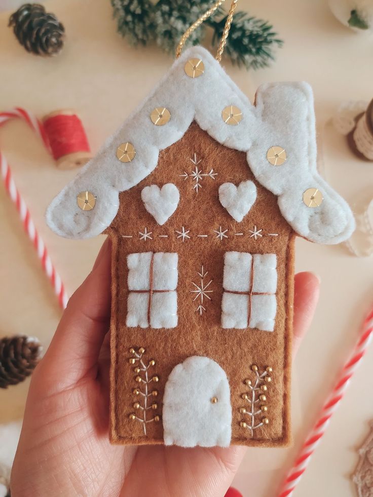 a gingerbread house ornament being held by someone