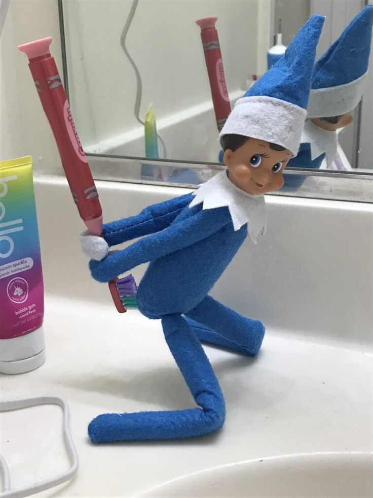 an elf is holding two toothbrushes in front of a bathroom mirror and sink