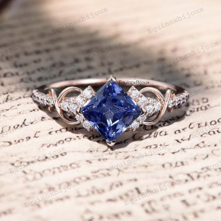 a blue diamond ring sitting on top of an old book