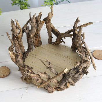 a bowl made out of driftwood sitting on top of a white table next to coins