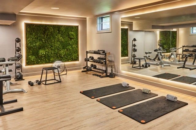 a gym with exercise equipment and mirrors in the wall that are illuminated by recessed lights