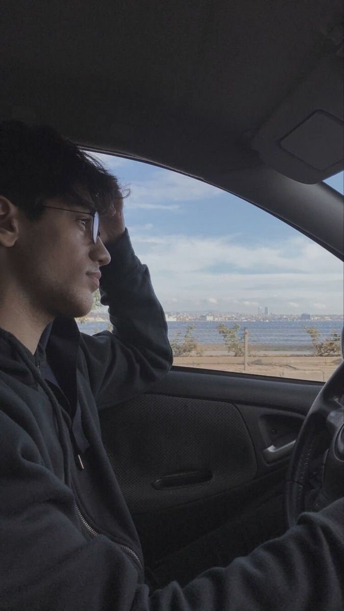 a man sitting in the driver's seat of a car looking out at the ocean