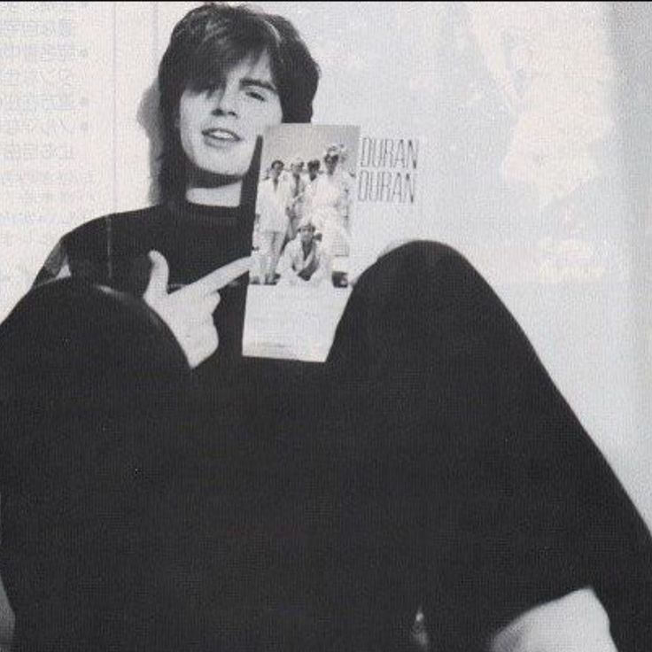 a person sitting on a couch with a book in their hand and holding up a peace sign