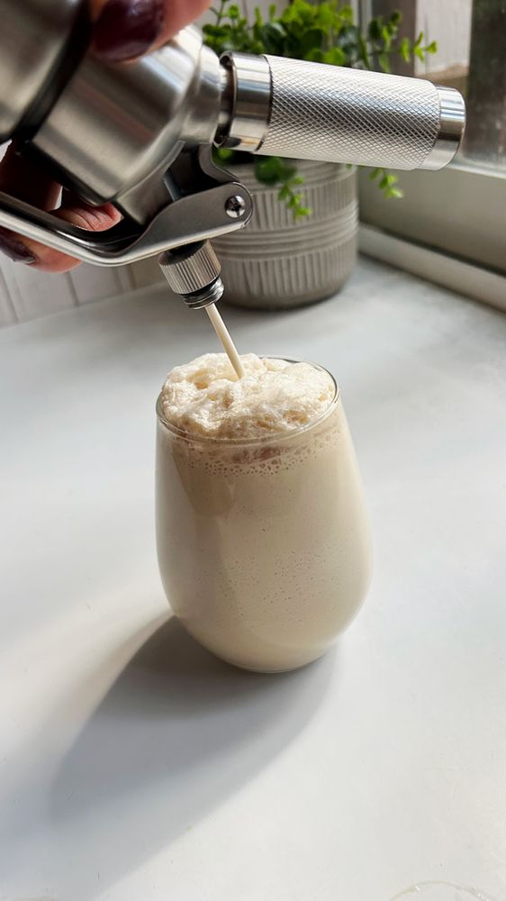 a person is pouring something into a cup with a metal faucet on it