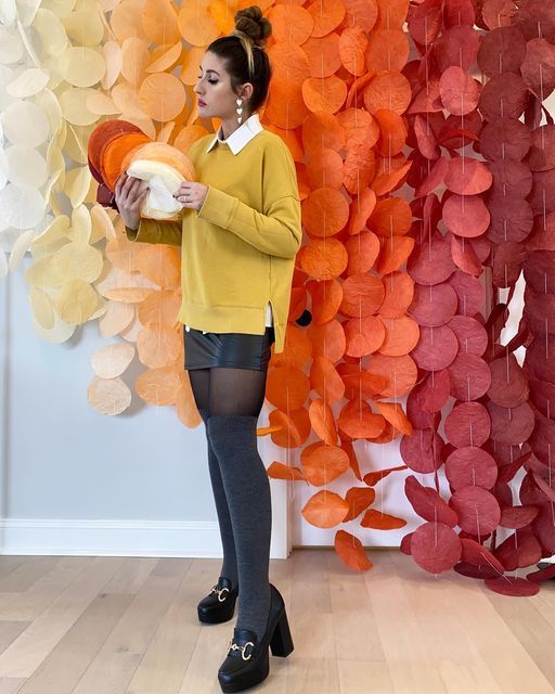 a woman standing in front of a colorful wall holding a bowl and looking at something