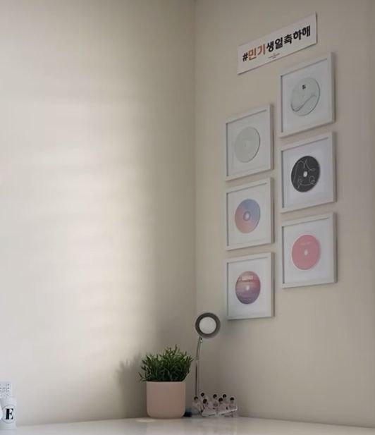 a white desk topped with a potted plant and pictures on the wall above it