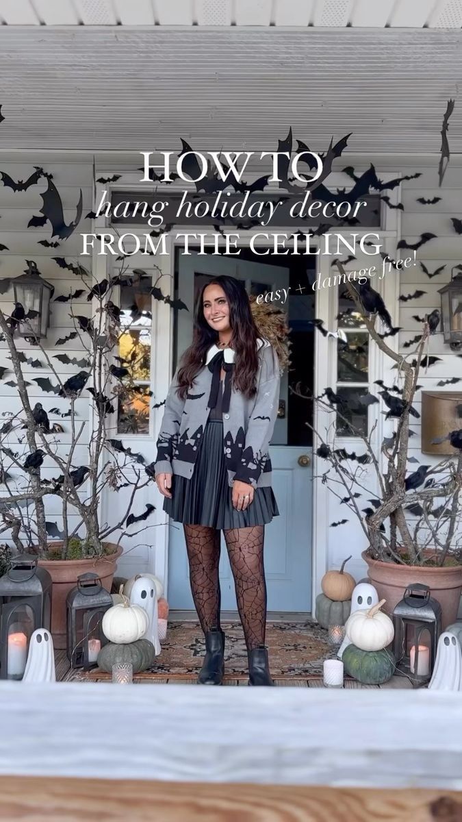 a woman standing in front of a house with bats on the door and halloween decorations behind her