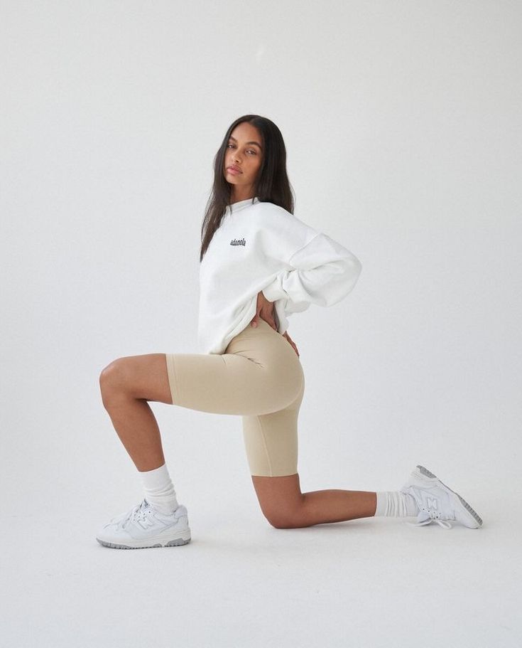 a woman is posing for the camera in her sports outfit and leggings, with one foot on the ground