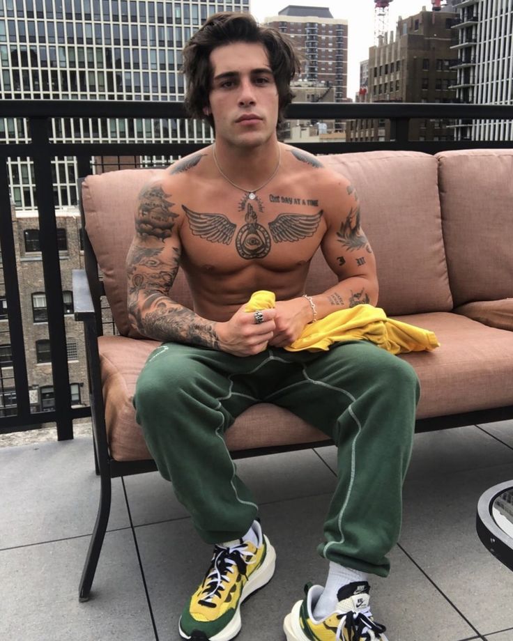 a man with tattoos sitting on a bench