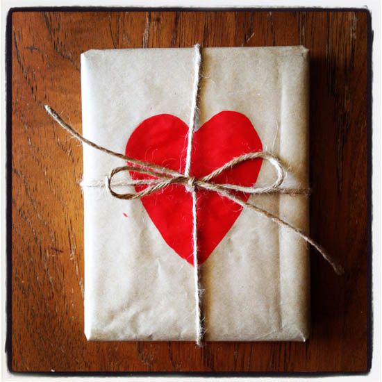 a wrapped gift with a red heart on it sitting on top of a wooden table