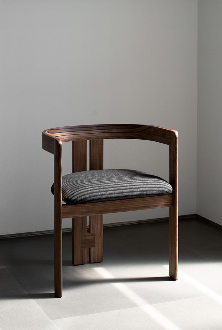 a wooden chair sitting on top of a floor next to a white wall in a room