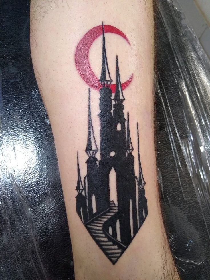 a tattoo on the leg of a person with a castle and moon in the background