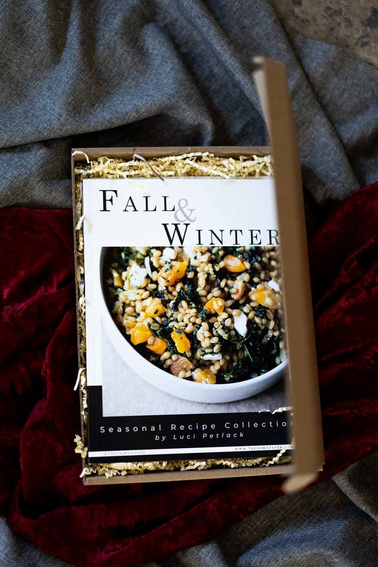 a cookbook sitting on top of a bed next to a red comforter and blanket