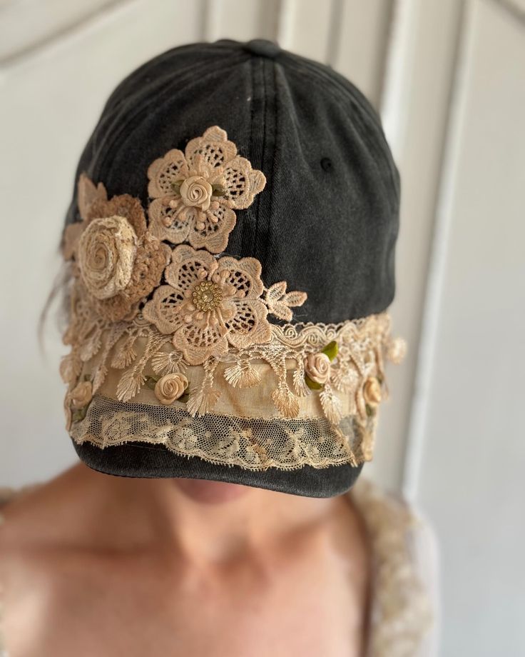 a woman wearing a black hat with flowers on it's brim and lace