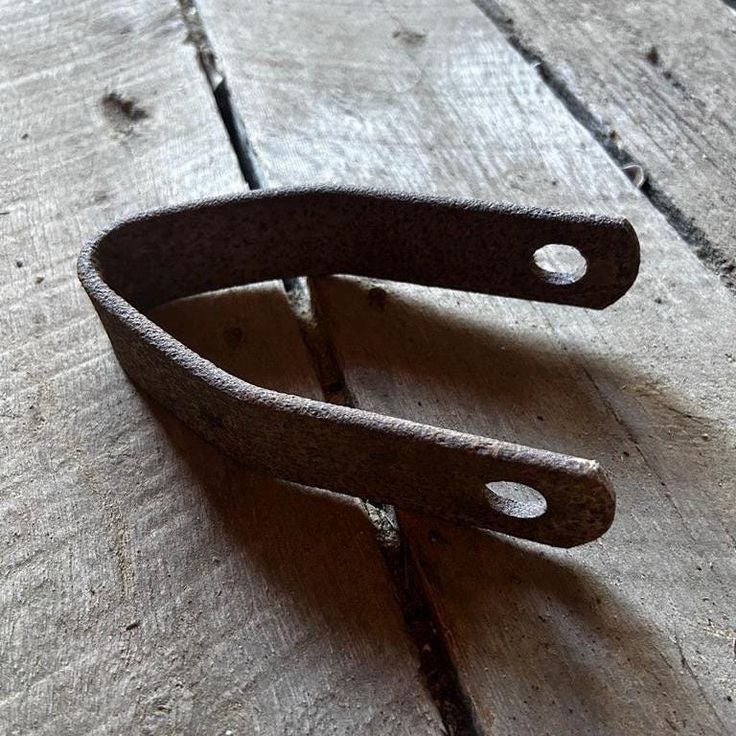 an old pair of scissors sitting on top of a wooden table next to a piece of wood