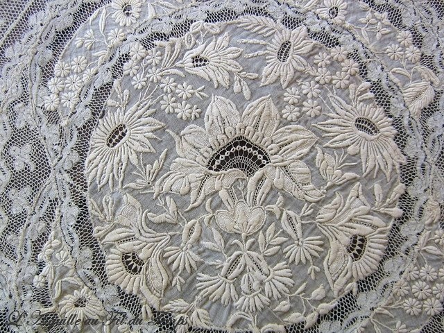 an intricate white lace with flowers on it