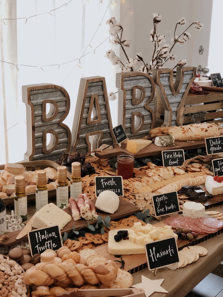 an assortment of cheeses and meats on display at a baby shower