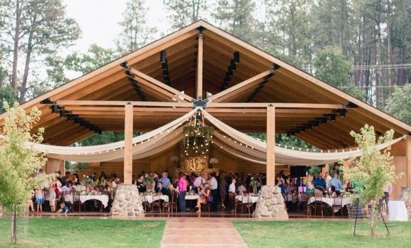 an outdoor wedding venue with people sitting at tables under a tent and trees in the background