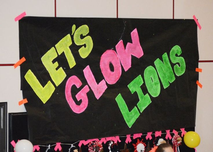 there is a sign that says let's glow lions on the wall with balloons and streamers