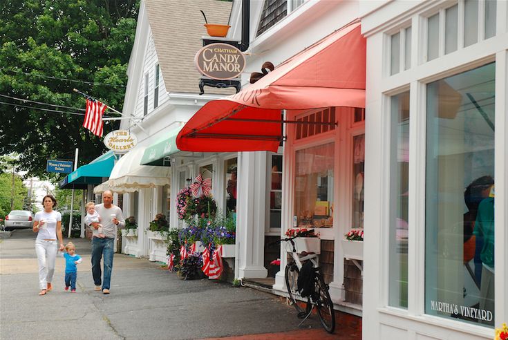 two women and a child walking down the street in front of shops with red awnings