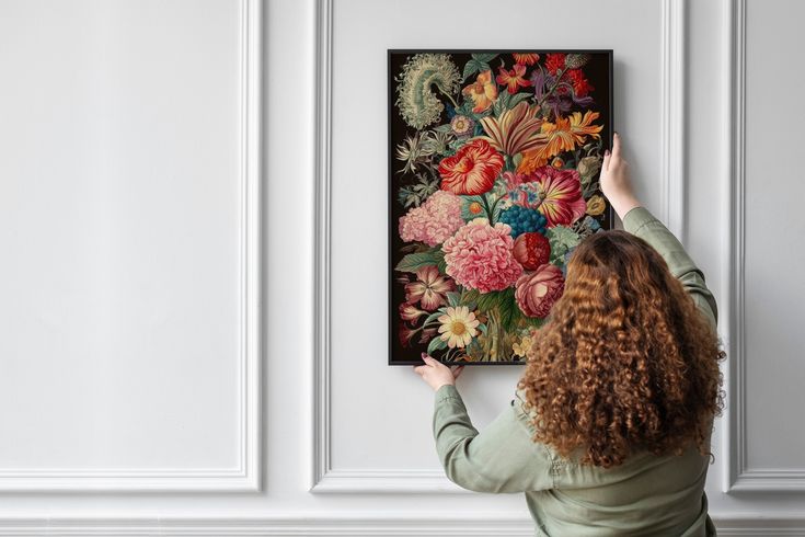 a woman is looking at a painting on the wall with her hands in the air