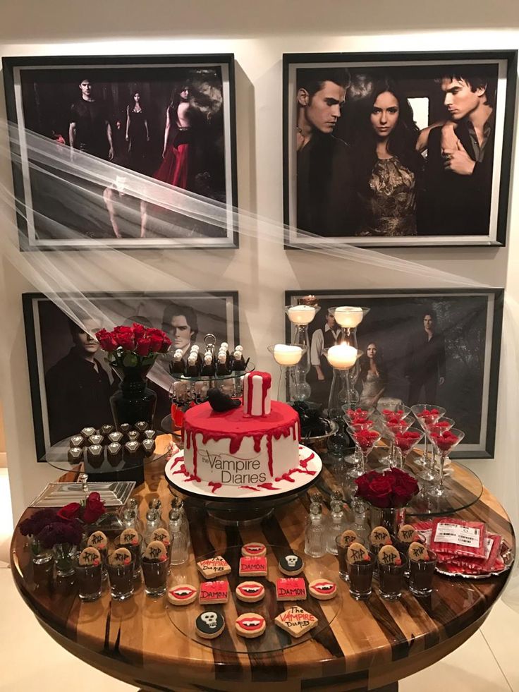 a table topped with a red and white cake covered in frosting next to pictures