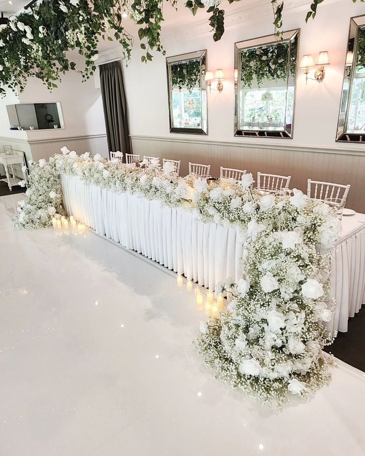 a long table covered in white flowers and greenery