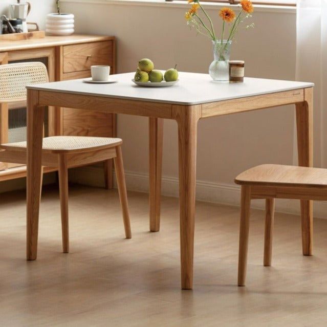 a small table with two chairs next to it in front of a window and flowers