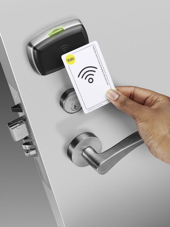 a hand holding a card that is in front of an electronic door lock with a fingerprint on it