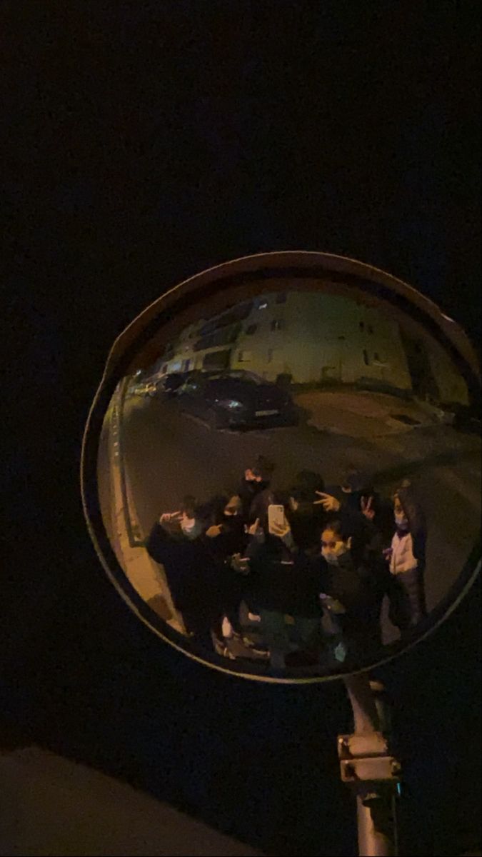 a group of people standing in front of a mirror on the side of a road