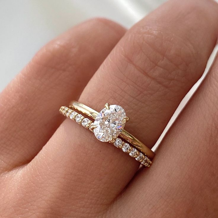 a woman's hand with two gold rings on her fingers and a diamond ring in the middle