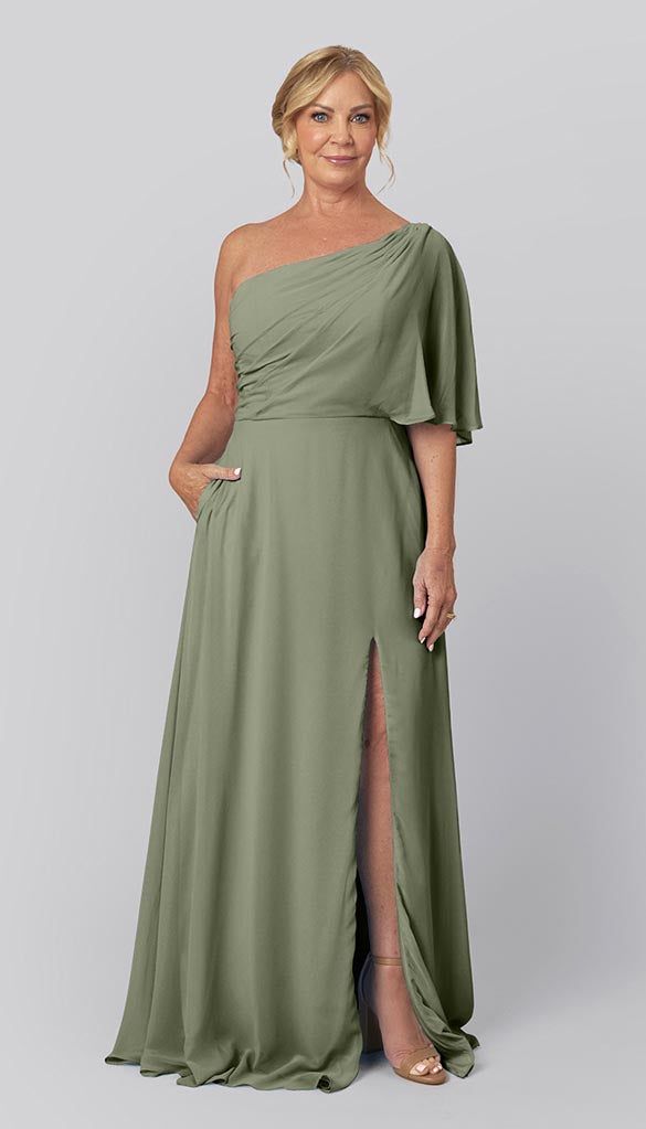 a woman in a long green dress with one leg slited out and her hand on her hip