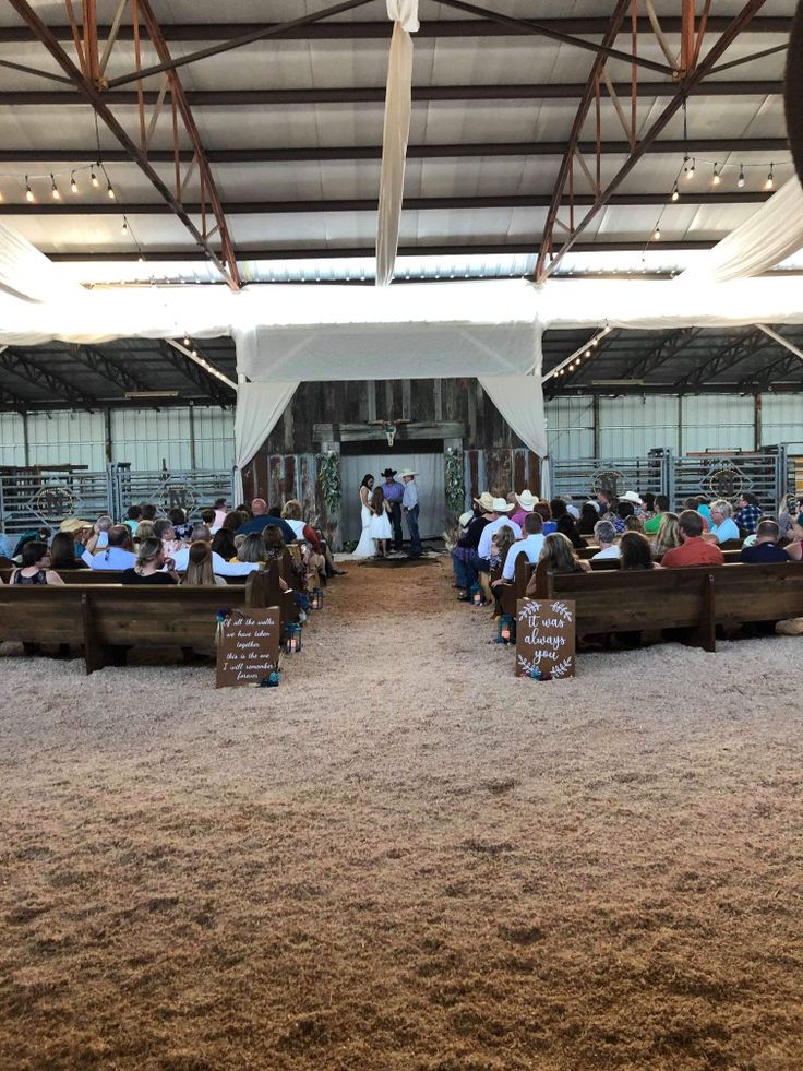 people are sitting on benches in the middle of an indoor area with sand and grass