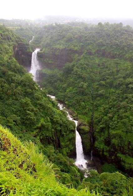 a large waterfall surrounded by lush green trees