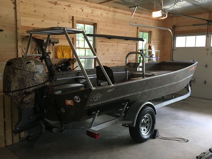 a boat is parked in a garage next to a cart with a large piece of equipment on it